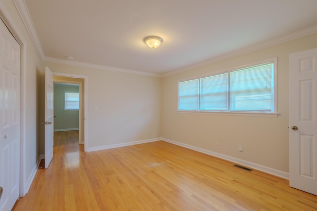 unfurnished room featuring baseboards, crown molding, visible vents, and light wood-style flooring