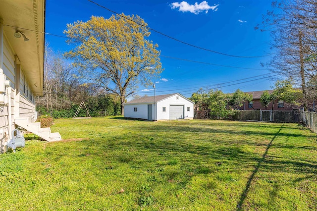 view of yard featuring a garage, an outbuilding, and fence