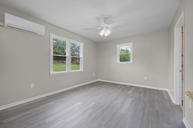 spare room with an AC wall unit, ceiling fan, and light hardwood / wood-style flooring