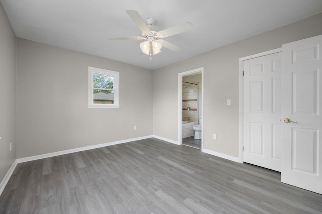 unfurnished bedroom with ceiling fan, a closet, ensuite bathroom, and hardwood / wood-style flooring