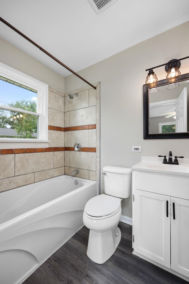 full bathroom featuring hardwood / wood-style floors, vanity, toilet, and tiled shower / bath combo