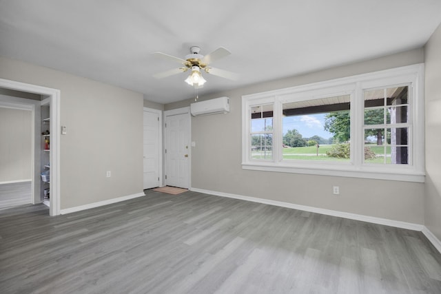 unfurnished bedroom with an AC wall unit, ceiling fan, and light wood-type flooring