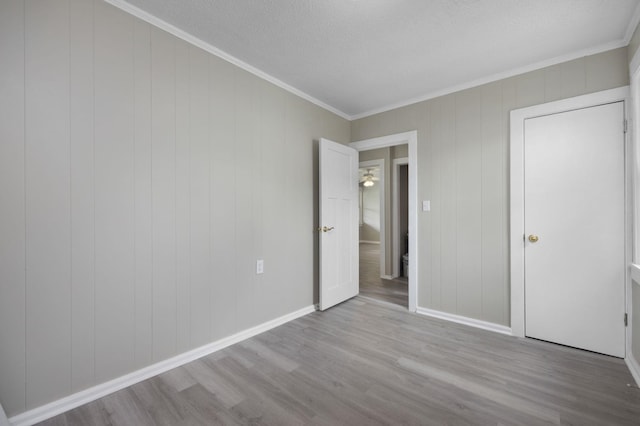 unfurnished bedroom featuring ornamental molding, a textured ceiling, and light hardwood / wood-style flooring