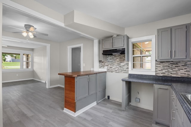 kitchen featuring gray cabinetry, ceiling fan, backsplash, and light hardwood / wood-style flooring