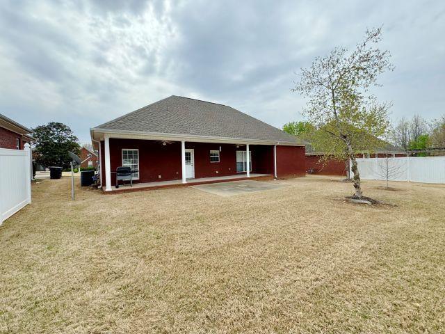 back of house featuring fence and a lawn