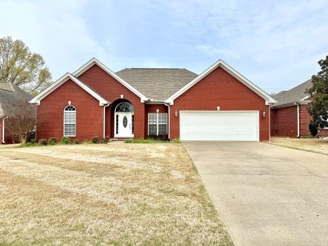 ranch-style house with driveway, a front yard, an attached garage, and brick siding