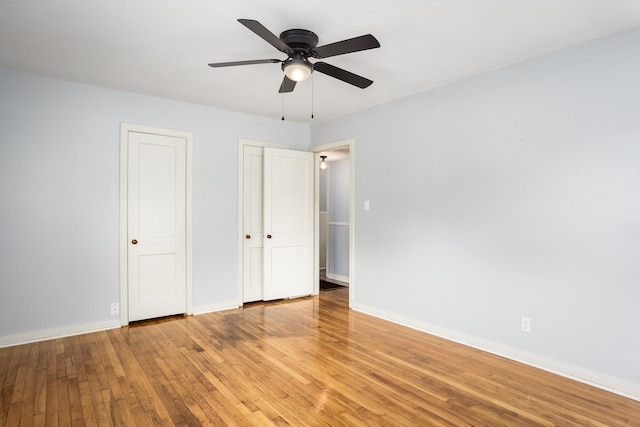 unfurnished bedroom with light wood finished floors, baseboards, a ceiling fan, and multiple closets