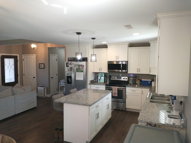 kitchen featuring white cabinetry, hanging light fixtures, stainless steel appliances, light stone countertops, and dark wood-type flooring