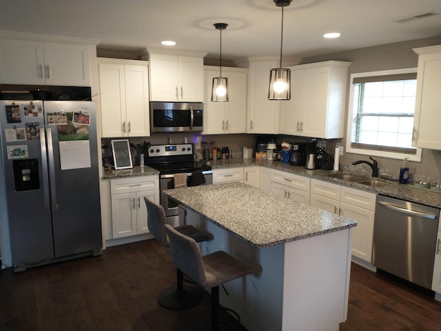 kitchen with pendant lighting, sink, stainless steel appliances, and white cabinets