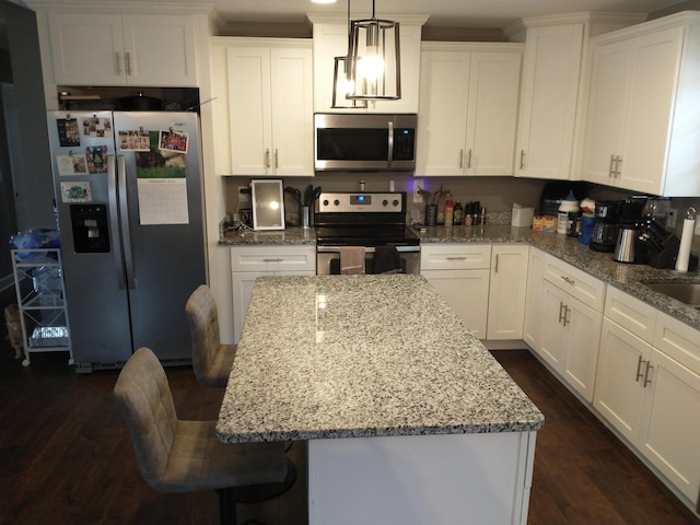 kitchen with white cabinetry, stainless steel appliances, decorative light fixtures, and a center island