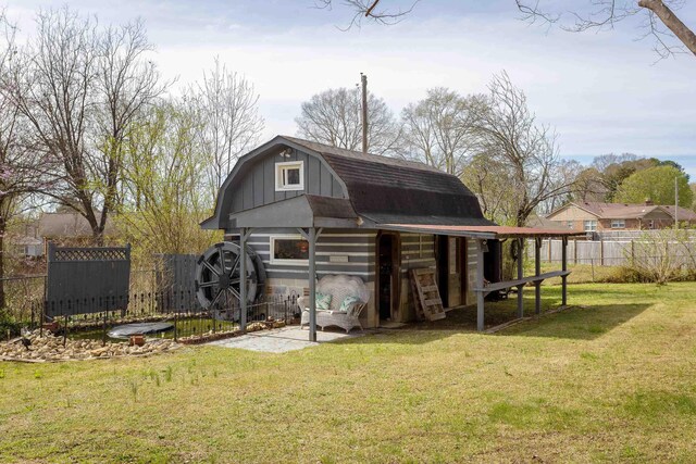  - view of barn featuring a lawn and fence