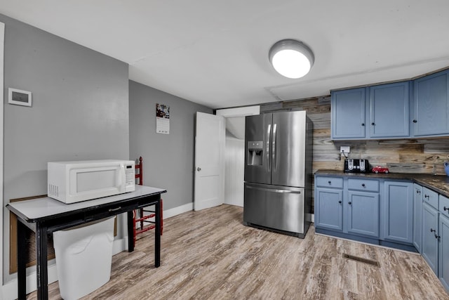  - kitchen with stainless steel refrigerator with ice dispenser, white microwave, blue cabinets, and light wood-style floors