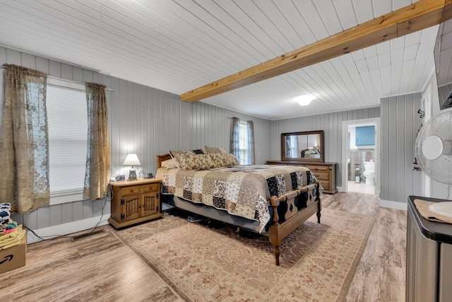  - bedroom featuring light wood-style floors, beamed ceiling, ensuite bath, and wood walls