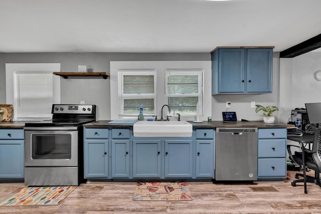  - kitchen featuring stainless steel appliances, blue cabinetry, open shelves, and dark countertops
