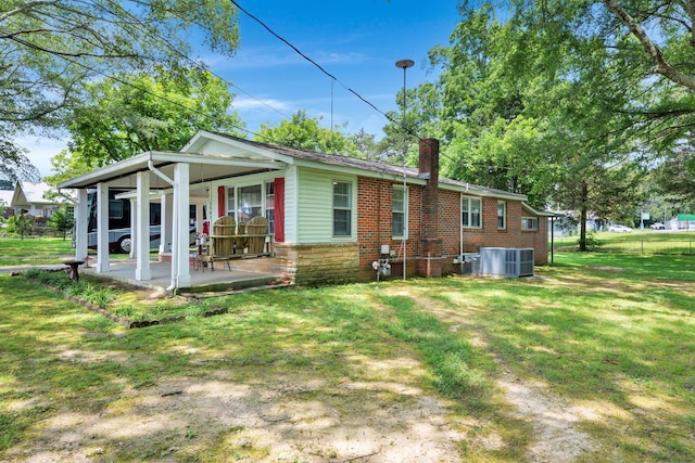  - rear view of house with a chimney, a lawn, and a patio