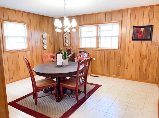 dining area featuring a notable chandelier and wood walls