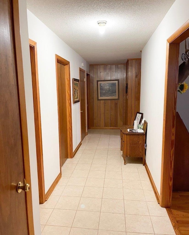 hallway with a textured ceiling and wooden walls