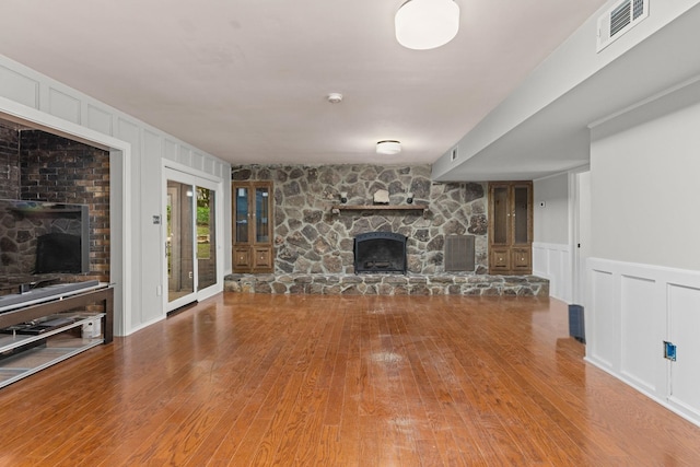 unfurnished living room featuring a fireplace, hardwood / wood-style flooring, and a decorative wall
