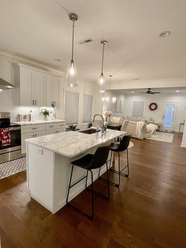 kitchen featuring stainless steel range with electric cooktop, white cabinets, a center island with sink, sink, and ceiling fan