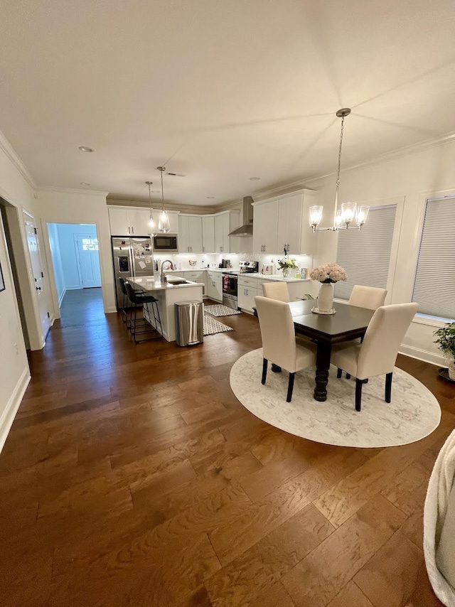 dining area featuring sink, dark wood-type flooring, a notable chandelier, and ornamental molding