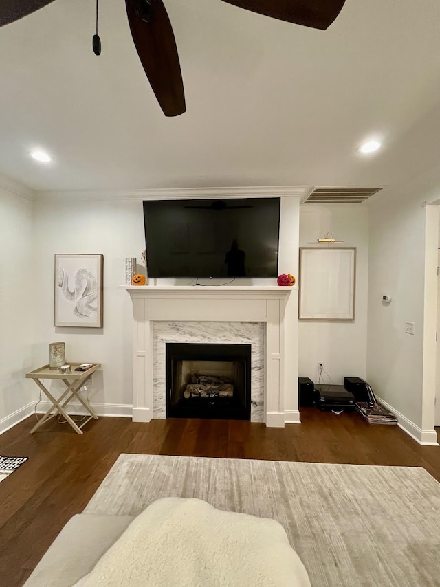 living room featuring a premium fireplace, ceiling fan, dark hardwood / wood-style floors, and ornamental molding