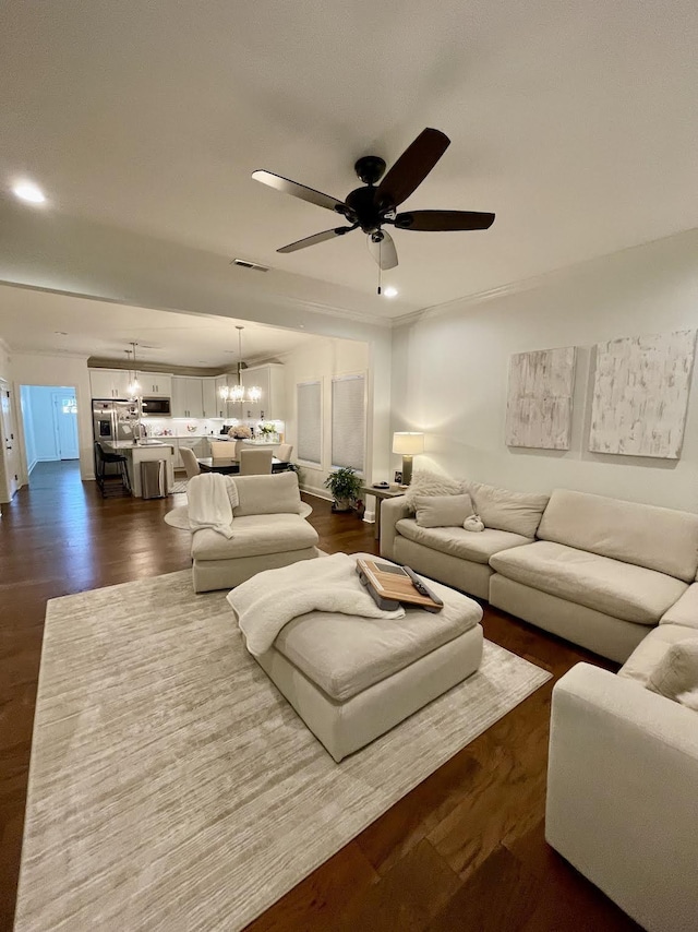 living room featuring ceiling fan with notable chandelier and dark hardwood / wood-style floors