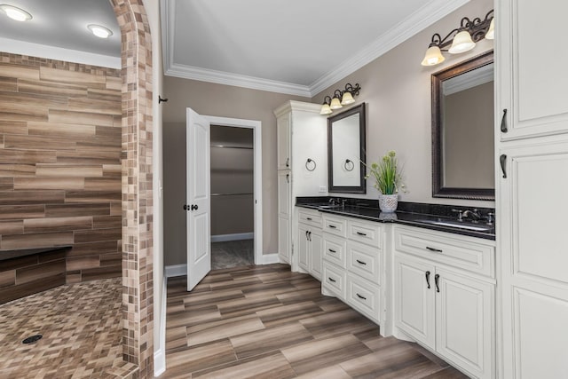 full bathroom featuring a tile shower, a sink, double vanity, wood finished floors, and ornamental molding