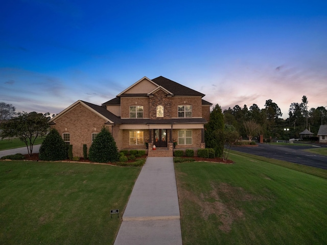 traditional-style house with covered porch, brick siding, and a front yard