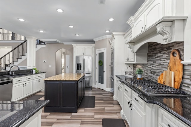 kitchen featuring recessed lighting, white cabinetry, arched walkways, a sink, and stainless steel appliances