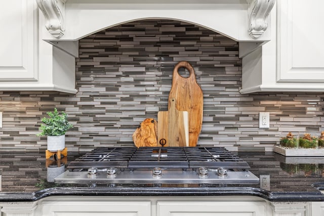 room details featuring decorative backsplash, white cabinetry, and stainless steel gas stovetop
