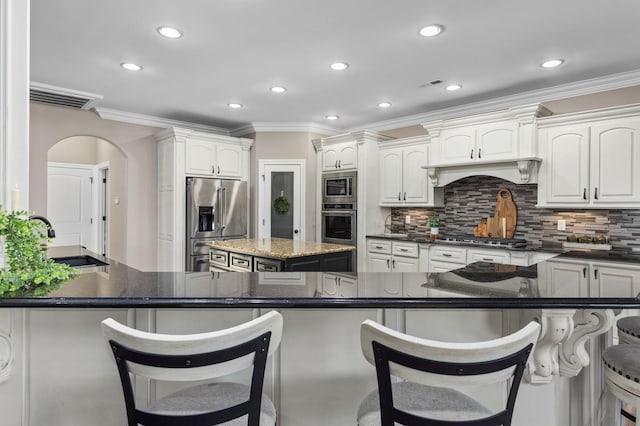 kitchen featuring crown molding, a sink, arched walkways, stainless steel appliances, and visible vents