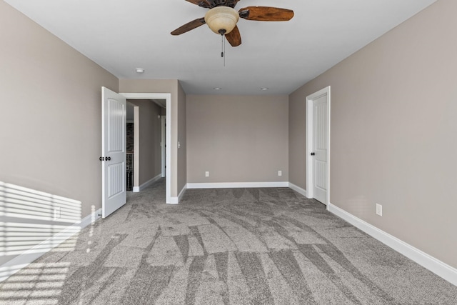 carpeted empty room featuring baseboards and ceiling fan