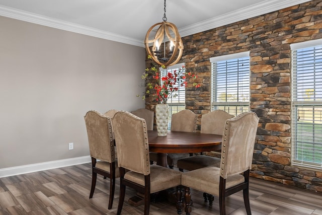 dining area featuring baseboards, ornamental molding, wood finished floors, and a chandelier