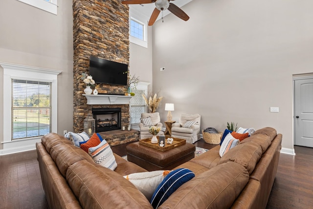 living area featuring baseboards, a ceiling fan, a towering ceiling, and wood finished floors