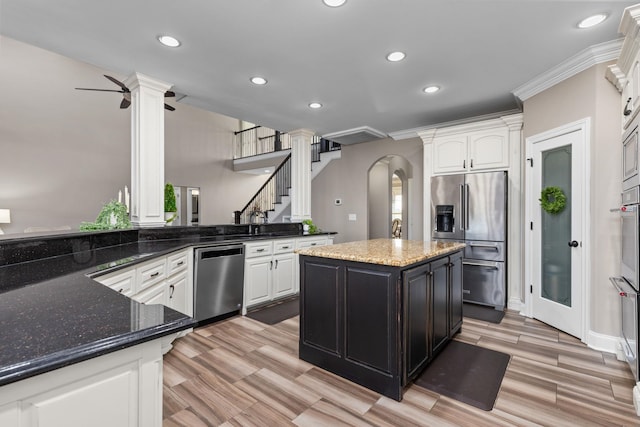 kitchen with decorative columns, arched walkways, stainless steel appliances, recessed lighting, and white cabinetry