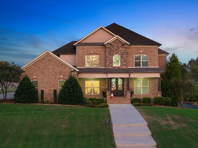 view of front of home with covered porch, brick siding, and a front lawn