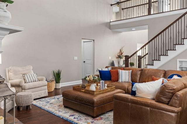 living area with baseboards, stairs, wood finished floors, and a towering ceiling