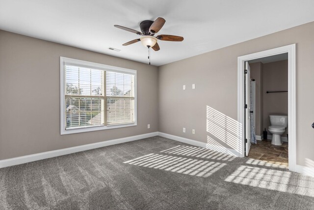 unfurnished bedroom featuring carpet flooring, ensuite bath, a ceiling fan, baseboards, and visible vents