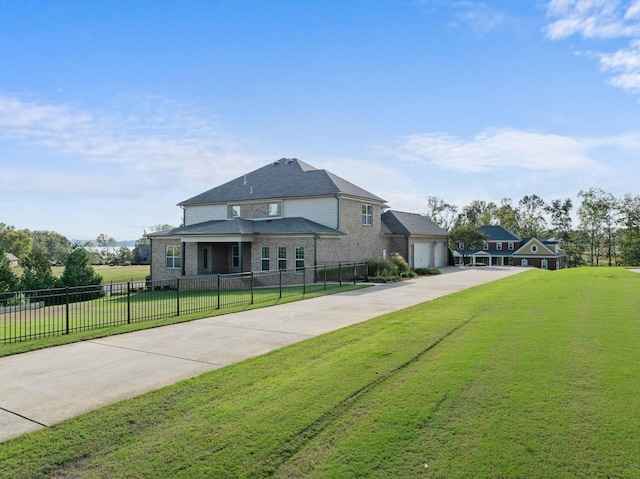 view of front of property featuring fence, concrete driveway, brick siding, and a front yard