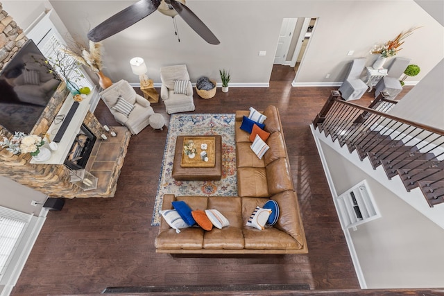 living room featuring a ceiling fan, a fireplace, wood finished floors, baseboards, and stairs