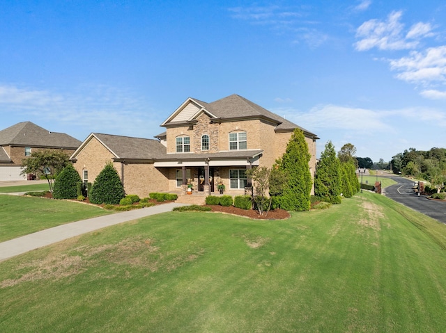traditional-style home featuring a porch, a front lawn, and brick siding