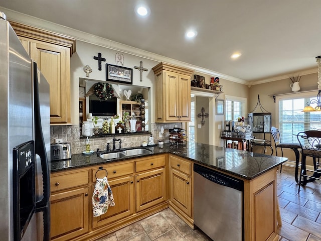 kitchen with pendant lighting, sink, dark stone countertops, appliances with stainless steel finishes, and kitchen peninsula