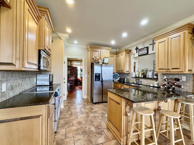 kitchen featuring a breakfast bar, dark stone countertops, ornamental molding, light brown cabinetry, and stainless steel appliances