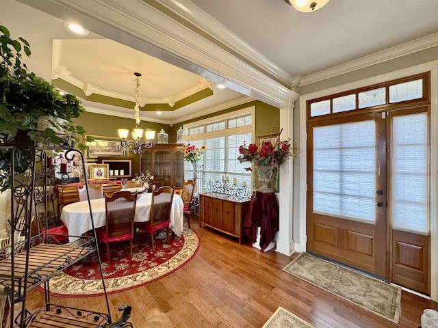 dining room featuring a raised ceiling, crown molding, hardwood / wood-style floors, and a notable chandelier