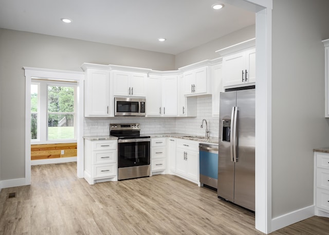 kitchen with a sink, white cabinetry, tasteful backsplash, and stainless steel appliances