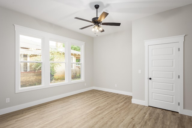 empty room with baseboards, a ceiling fan, and light wood finished floors