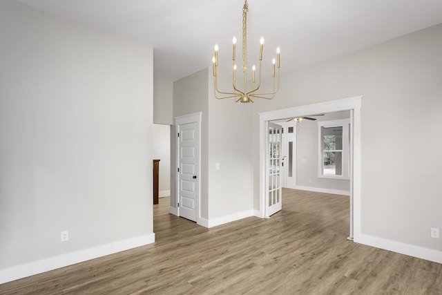 unfurnished dining area featuring baseboards, ceiling fan with notable chandelier, and wood finished floors