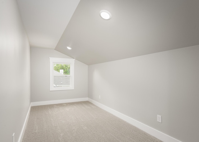 bonus room featuring baseboards, vaulted ceiling, and light colored carpet