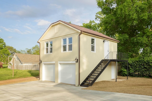 view of home's exterior with stairway, an attached garage, driveway, and stucco siding