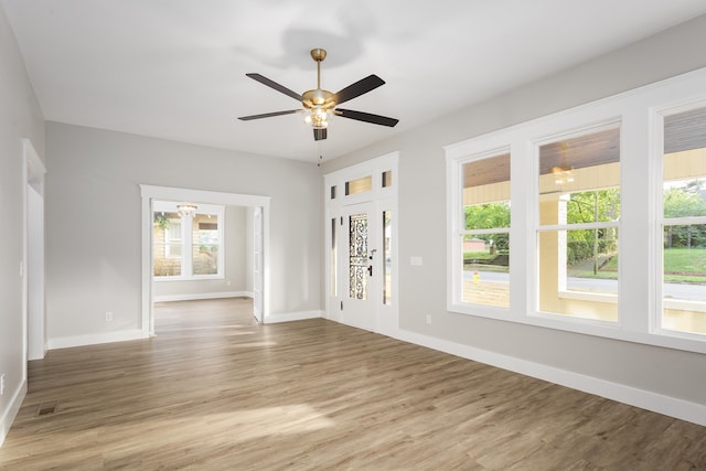 interior space with a healthy amount of sunlight, baseboards, ceiling fan, and wood finished floors
